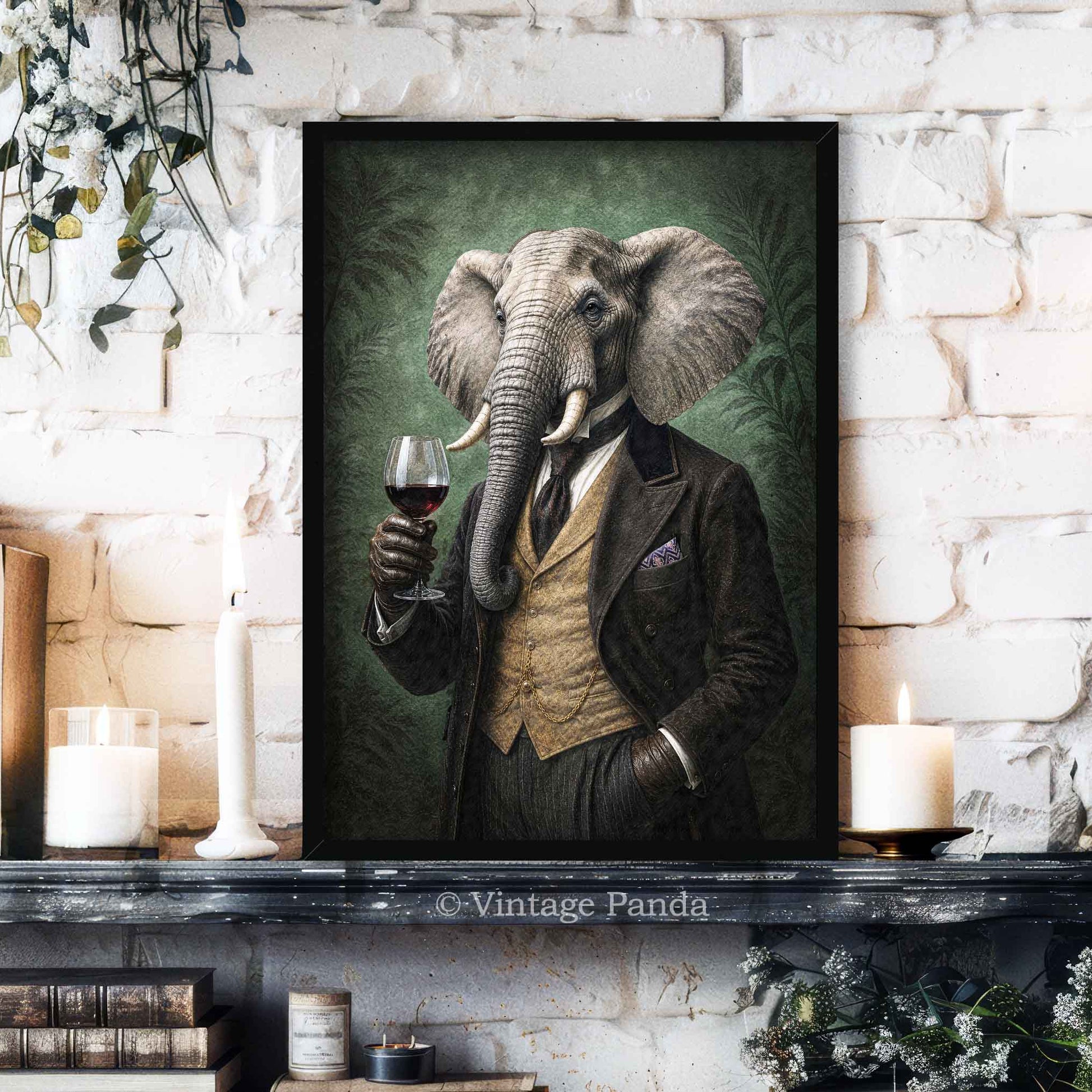 A framed vertical art print of an elephant dressed in a vintage suit and holding a glass of red wine, displayed on a dark mantelpiece against a white brick wall with candles and books.