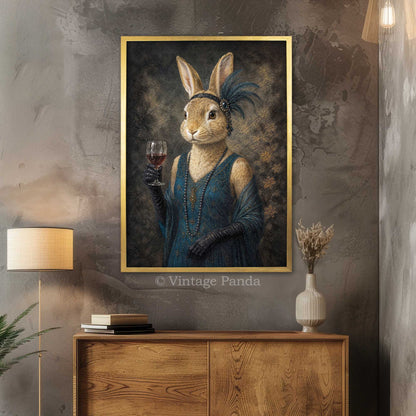 A framed vertical portrait print of a rabbit dressed in a blue evening gown and black gloves, holding a wine glass, displayed on a textured gray wall above a wooden console table in a styled interior.